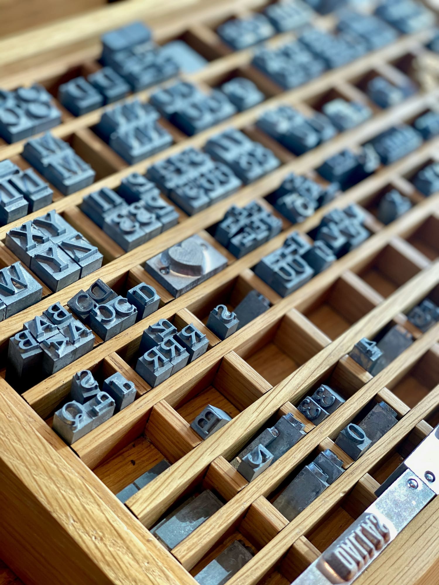A wooden letterpress type case filled with metal letters.
